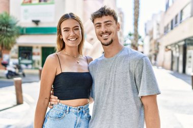 Genç İspanyol çift mutlu bir şekilde gülümsüyor ve şehirde birbirlerine sarılıyorlar..