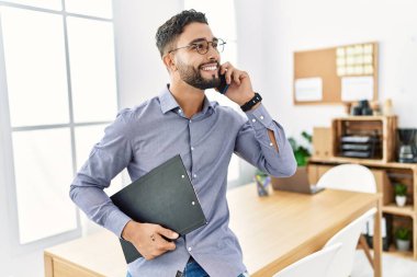 Genç Arap adam ofisteki akıllı telefondan konuşarak kendine güveniyor.