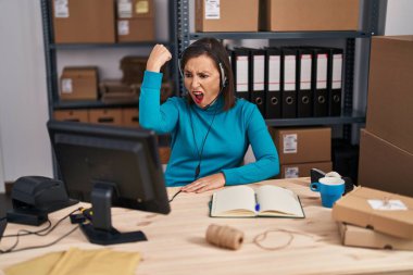 Middle age hispanic woman working at small business ecommerce on customer support annoyed and frustrated shouting with anger, yelling crazy with anger and hand raised 