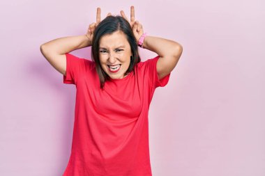 Middle age hispanic woman wearing casual clothes posing funny and crazy with fingers on head as bunny ears, smiling cheerful 