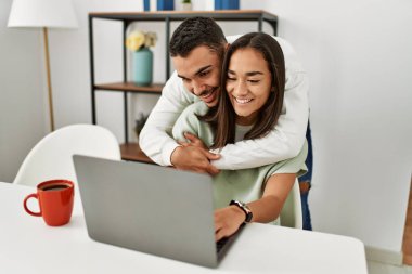 Laptop kullanan ve evde kahve içen genç bir çift..