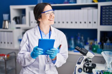 Young woman scientist using touchpad at laboratory