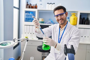 Laboratuvarda pipeti kullanarak sıvıyı ölçen genç İspanyol bilim adamı.