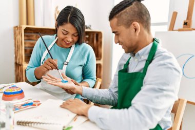 Genç Latin ressam çift gülümsüyor resim stüdyosunun masasında mutlu bir resim çiziyor.