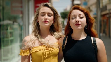 Two women hugging each other breathing at street