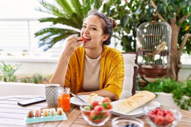 Genç İspanyol kız kahvaltı yapıyor terasta masada oturuyor..