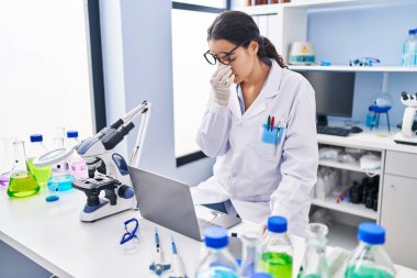 Genç İspanyol kadın bilim adamı üniforması giyiyor. Laboratuvarda çalışmanın stresi.