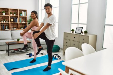 Genç Latin sporcu çift gülümseyerek evde mutlu bir antrenman yapıyor..