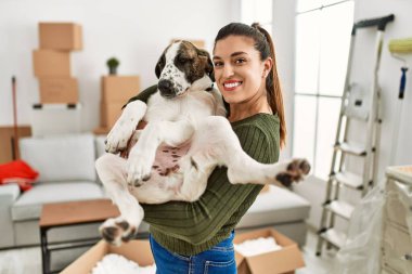 Genç bayan gülümsüyor. Kendine güvenen, kucaklayan köpek evde.