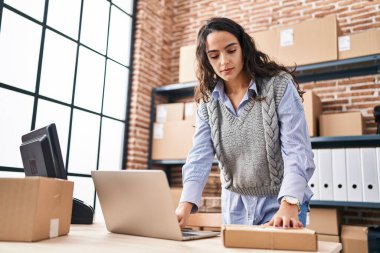 Ofiste dizüstü bilgisayar kullanan Latin kökenli genç bir iş adamı.