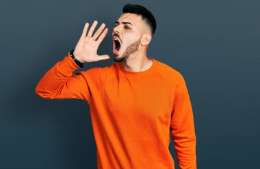 Sakallı, günlük turuncu kazak giyen, el ele tutuşup bağıran genç bir İspanyol. iletişim konsepti. 