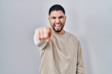 Genç yakışıklı adam izole edilmiş arka planda dikiliyor. Kameraya kızgın ve sinirli olduğunu gösteriyor. 