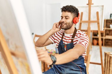 Sanat stüdyosunda müzik dinleyen genç bir Arap sanatçı..