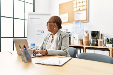Ofiste çalışan üst düzey Afro-Amerikan iş kadını laptopu kullanıyor.