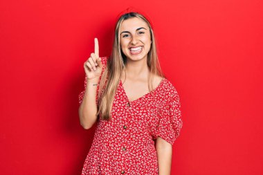 Güzel İspanyol kadın yaz elbisesi giyer ve bir numarayı göstererek gülümserken kendinden emin ve mutludur.. 