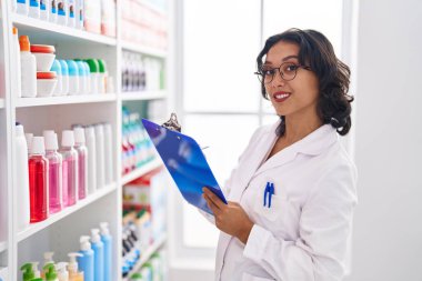 Genç, güzel İspanyol kadın eczacı eczanedeki belgeye yazı yazıyor.