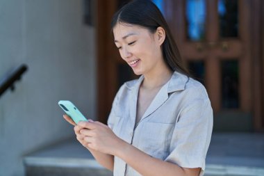 Sokakta akıllı telefon kullanan kendine güvenen Çinli bir kadın.