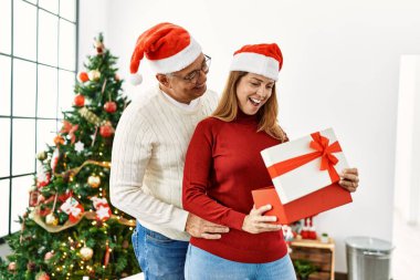 Orta yaşlı İspanyol çift mutlu bir şekilde gülümsüyor ve evde Noel hediyelerini açıyor..