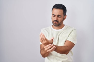 Sakallı İspanyol bir adam arka planda duruyor. Ellerinde ve parmaklarında ağrı, iltihap var. 