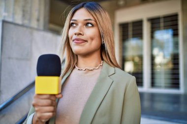 Sokakta mikrofon kullanan kendine güvenen genç Latin kadın.