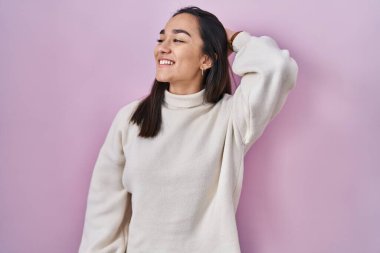 Pembe arka planda duran genç Güney Asyalı kadın. Kendine güvenen, el hareketleriyle saçlarına dokunan, çekici ve modaya uygun poz veren. 