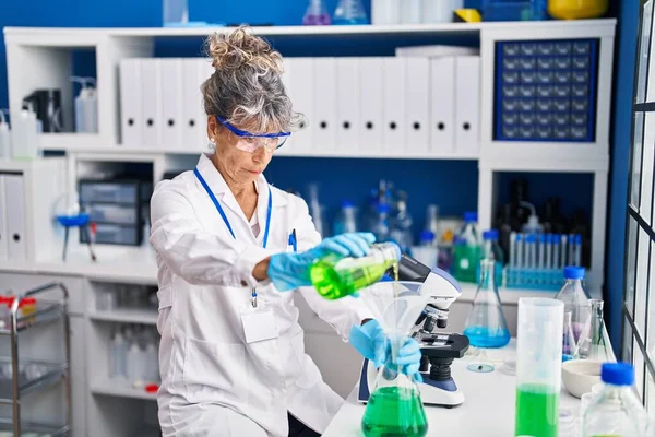 研究室で液体を測定する中年女性科学者 — ストック写真