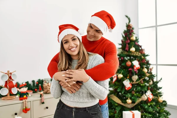 Pareja Joven Abrazando Sonriendo Feliz Vistiendo Sombrero Navidad Casa — Foto de Stock