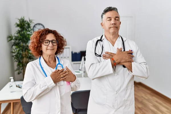 Two Middle Age Doctors Medical Clinic Smiling Hands Chest Closed — Foto Stock