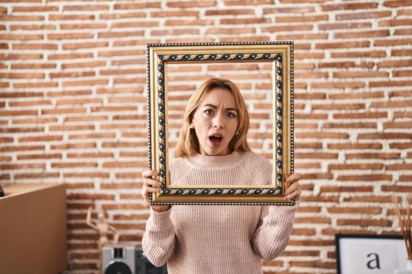 Hispanic Woman Holding Empty Frame Shock Face Looking Skeptical Sarcastic — Stock Photo, Image