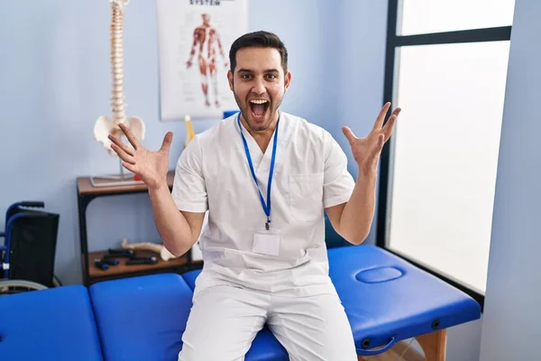 Young Hispanic Man Beard Working Pain Recovery Clinic Celebrating Crazy — Foto de Stock