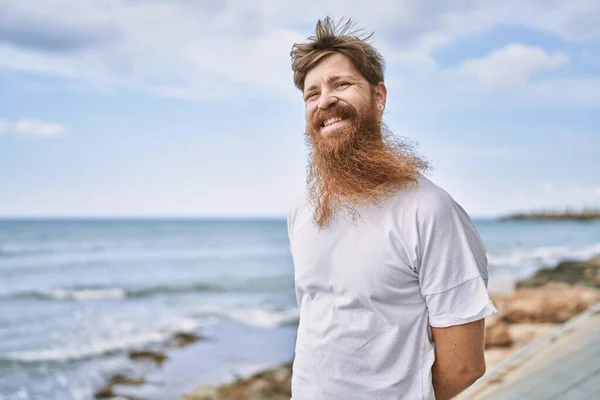 Young redhead man smiling happy standing at the beach.