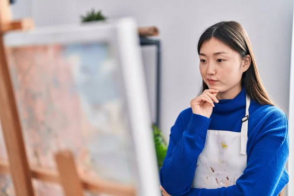 Chinese woman artist looking draw with doubt expression at art studio