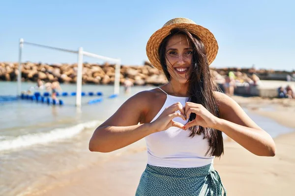 Joven Mujer Hispana Sonriendo Confiada Haciendo Gesto Corazón Con Las —  Fotos de Stock