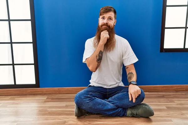 Redhead Man Long Beard Sitting Floor Empty Room Looking Confident — Stockfoto