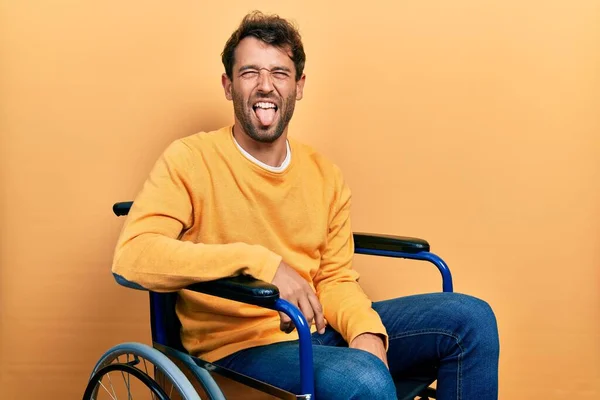 面白い表情で楽しそうに舌を突き出している車椅子に髭を生やしたハンサムな男 感情の概念 — ストック写真