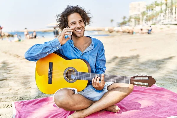 Young Hispanic Man Playing Guitar Talking Smartphone Sitting Sand Beach — Stock Photo, Image