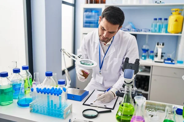 Genç İspanyol bilim adamı elinde değerli taşla laboratuardaki belgeye yazı yazıyor.