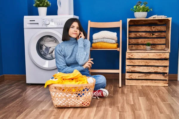 Young Hispanic Woman Laundry Room Serious Face Thinking Question Hand —  Fotos de Stock