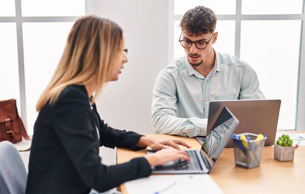 Young man and woman business workers using laptop working at office