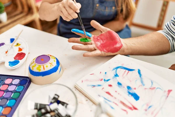 Couple painting hands at art studio.