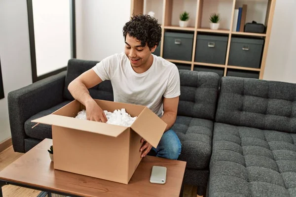 Jovem Hispânico Homem Unboxing Caixa Papelão Sentado Sofá Casa — Fotografia de Stock