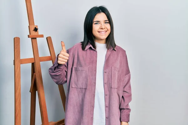 Young Brunette Woman Standing Empty Easel Stand Smiling Happy Positive — Stok fotoğraf