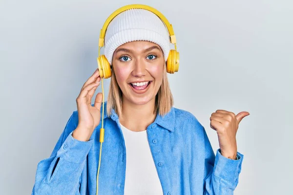 Красива Блондинка Слухає Музику Допомогою Навушників Спрямованих Великий Палець Сторону — стокове фото