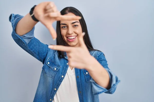 Hispanic Woman Standing Blue Background Smiling Making Frame Hands Fingers — Φωτογραφία Αρχείου