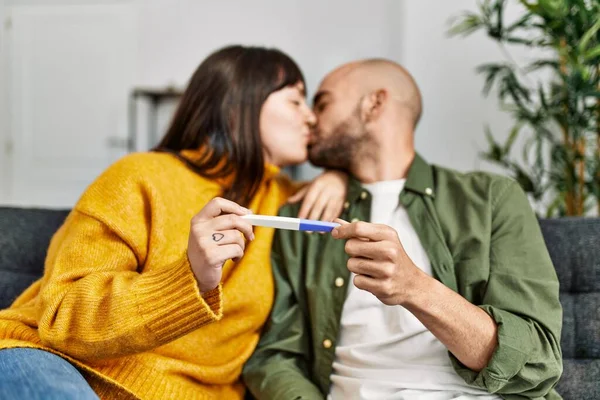 Genç İspanyol çift, evdeki kanepede oturup hamilelik testi yapıyorlar..