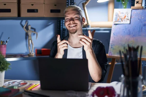 Young Caucasian Man Using Laptop Night Art Studio Pointing Fingers — Fotografia de Stock