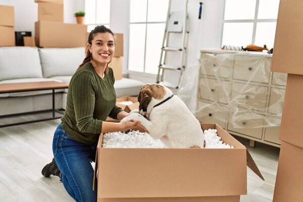 Молодая женщина улыбается уверенно играя с собакой дома