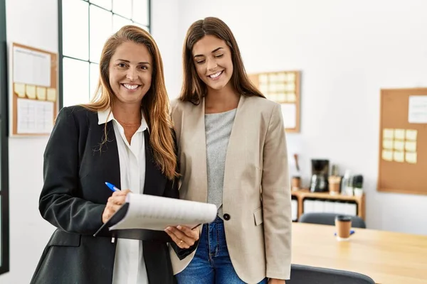 Mother and daughter business workers smiling confident reading document at office
