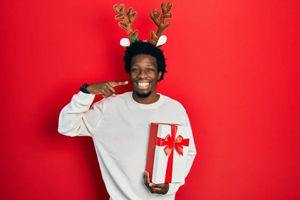Молодой Африканский Американец Рождественской Шляпе Подарком Улыбаясь Показывая Пальцами Зубы — стоковое фото