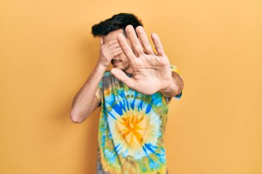 Latin kökenli genç bir adam, günlük kıyafetler giyip, elleriyle gözlerini kapatıyor ve üzgün ve korku ifadeleriyle jestleri durduruyor. utangaç ve olumsuz kavram. 